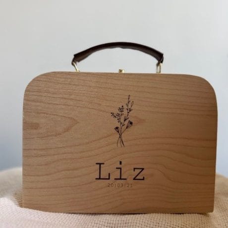 een houten koffertje met leren handvat gepersonaliseerd met naam en geboortedatum